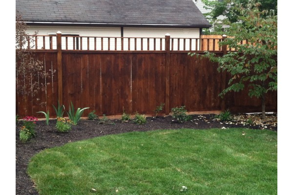 Dark wood fence along side of house and enclosing lawn.